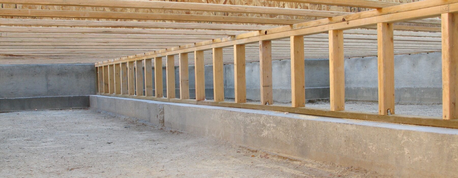 A view inside a clean, unfinished crawl space with exposed wooden framing and concrete foundation.